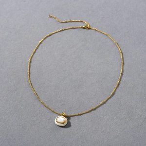 Detail of 18k gold plated necklace featuring an oval white shell stone pendant