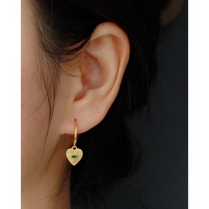 Gold heart drop earrings with green eye gemstone inlay on a female model