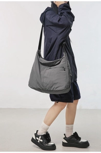 Model wearing a large grey nylon crossbody bag showing its spacious design and drape