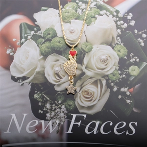 Golden necklace with heart gesture pendant and zircon star on romantic floral background