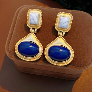Detail of vintage earrings with blue resin stones and gold milgrain frames on velvet