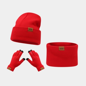 Close-up of red winter knit set featuring MOM leather patch and touchscreen gloves