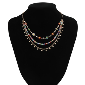 Detailed layered necklace featuring colorful beads and enamel flower charms on a model