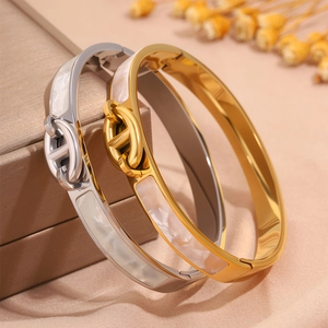 Detailed view of silver and gold titanium steel bangles with white mother-of-pearl inlay