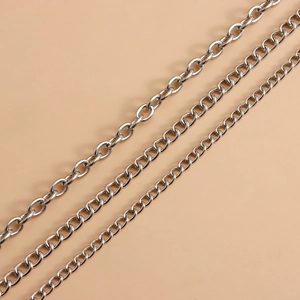 Detail of silver layered metal waist chains with hollow heart charms on beige background