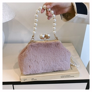 Detail of pink plush shell handbag with elegant pearl handle and gold chain strap