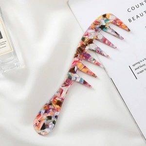 Colorful terrazzo acetate wide-tooth hair comb displayed on white silk with perfume