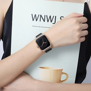 Detail of elegant black dial with golden case and black Milanese mesh strap on wrist