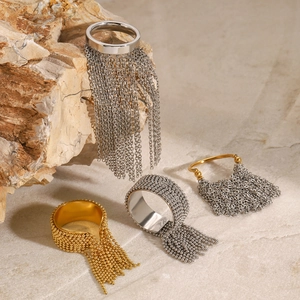 Set of four stainless steel tassel rings in gold and silver finish on a stone surface