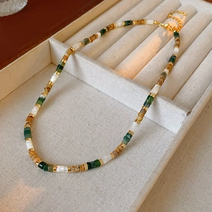 Macro detail of multi-colored pearl necklace with gold lobster clasp in a beige jewelry box