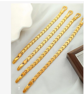 Detailed close-up of golden watch-band style chain bracelets on white silk background