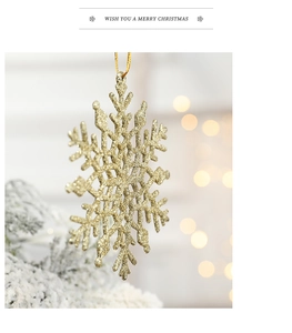 Close-up of a glittering gold plastic snowflake hanging on a festive Christmas tree branch