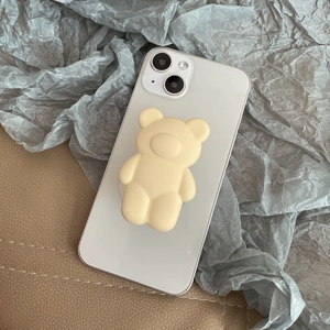 Detail view of a matte cream bear phone socket on a white smartphone against textured fabric