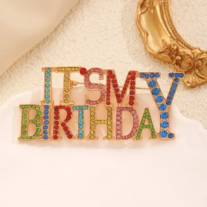 Detail view of a colorful rhinestone birthday brooch on a white ceramic plate