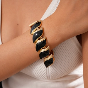 Détail du bracelet feuille vintage doré avec émail noir sur le poignet du modèle
