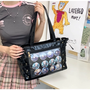 Close-up of black glossy ita bag with clear window displaying eleven anime character pins