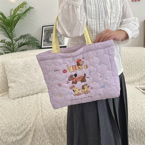 Detailed shot of purple quilted tote bag with cute embroidery shown in lifestyle setting