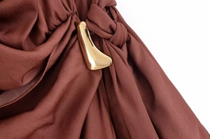 Detail van bruine satijnen stof met een elegante gouden metalen gesp op de halslijn