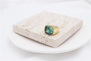 Macro detail of men's gold titanium ring featuring colorful abalone shell inlay