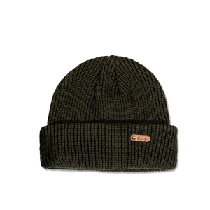 Detailed view of dark olive green knit hat with a classic deer head leather patch texture