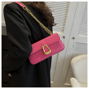 Detail showing fuchsia underarm bag with gold chain strap on a black blazer