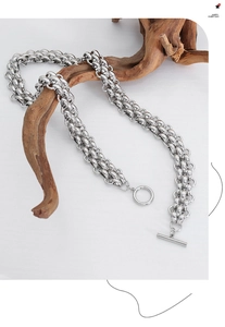 Detail of silver chunky chain necklace with toggle clasp on wooden stand