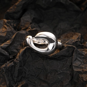 Silver liquid metal abstract ring with fluid geometric design on black textured paper