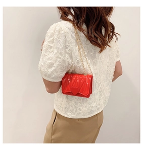 Detailed view of red silicone heart bag with gold chain strap on model's shoulder