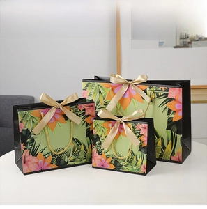 Three sizes of tropical floral gift bags with gold rope handles and champagne ribbon bows