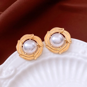 Macro detail of vintage gold spiral earrings featuring centered white pearls