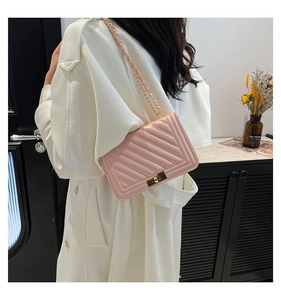Detailed view of a pink quilted leather shoulder bag with golden chain and square lock