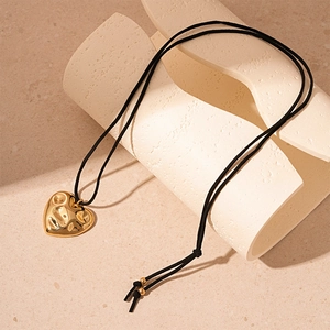 Detail of molten gold textured heart pendant with a minimalist black cord chain necklace