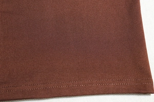 Détail macro de l'ourlet à double couture sur une robe marron foncé à manches longues