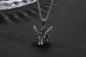 Détail d'un pendentif tête de dragon avec chaîne tressée noire sur un fond noir texturé