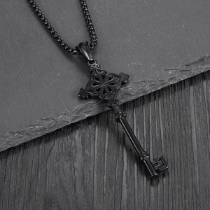 Detail view of black vintage key pendant with ornate cross patterns on a textured background