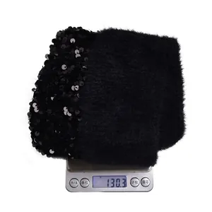 Winter black sequin knitted beanie with faux fur pom pom shown on a scale at 130.3g weight