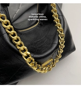Detail of vintage black quilted bag with high-shine leather and heavy gold chain