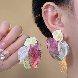 Macro shot of ivory resin flower earrings with green sequins and sheer mesh petals