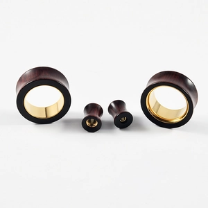 Detailed macro view of dark wood and gold metal inlay combination ear tunnel jewelry