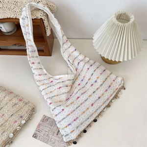 Detailed macro of white crochet hobo bag featuring rainbow stripes and sequin charms