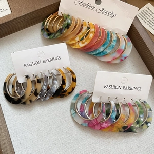 Flat lay of tortoiseshell acetate C-shaped earrings set on a wooden tray