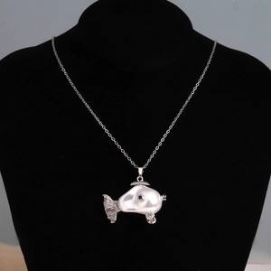 Detail of cute silver fish pendant with irregular pearl body on black velvet mannequin