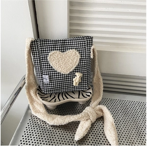 Détail du sac à bandoulière pied-de-poule avec patch cœur et breloque ours en peluche