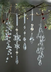 Transparent acrylic snowflake and teardrop pendants hanging on a decorated Christmas tree