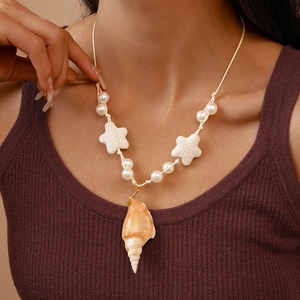 Close-up of ocean-style necklace with conch shell pendant, starfish beads, and white pearls