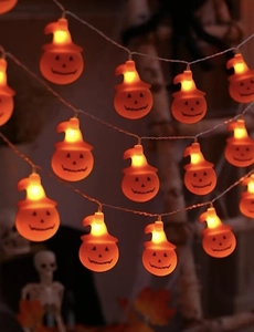 Detail of LED pumpkin string lights with hats emitting warm orange glow for Halloween decor