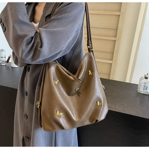 Detail of dark brown PU leather bag with vintage butterfly ornaments and zipper