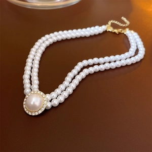Détail du collier de perles double épaisseur avec pendentif en strass et fermoir doré chic