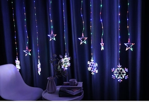 Star and snowflake LED string lights glowing against a dark blue curtain backdrop