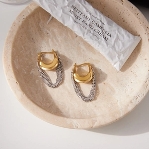 Boucles d'oreilles créoles dorées en U avec pompons argentés sur plateau en pierre